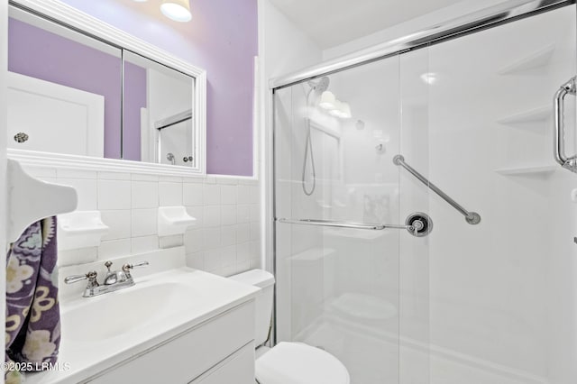 full bath featuring vanity, tile walls, toilet, and a stall shower