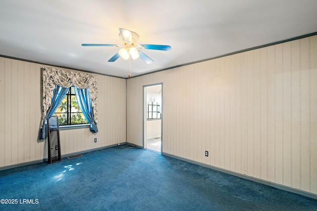 carpeted spare room featuring visible vents, baseboards, and ceiling fan