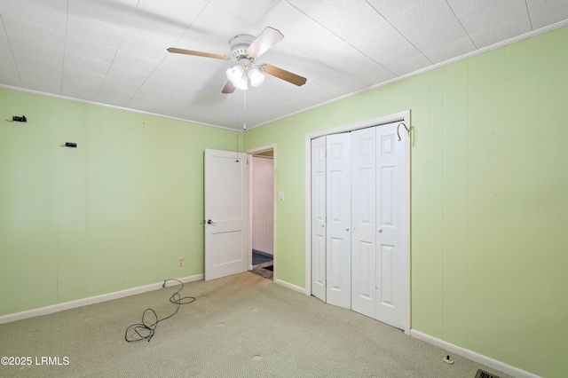 unfurnished bedroom featuring carpet flooring, baseboards, a closet, and ceiling fan