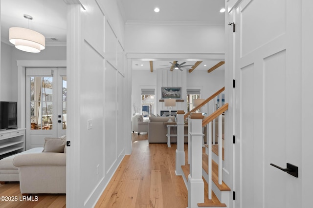 interior space featuring beamed ceiling, ornamental molding, and light hardwood / wood-style flooring