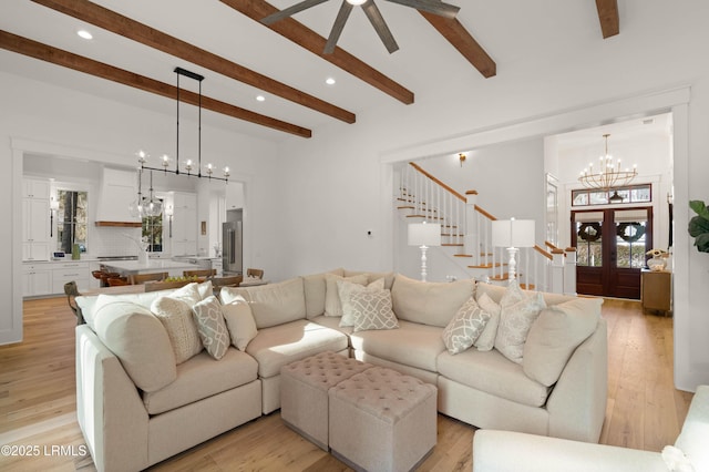 living room with beamed ceiling, plenty of natural light, a notable chandelier, and light wood-type flooring