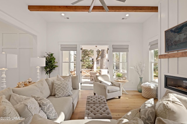 living room with ceiling fan, beam ceiling, and light hardwood / wood-style flooring