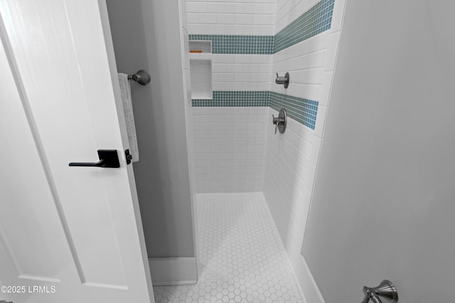 bathroom with tile patterned flooring and a tile shower