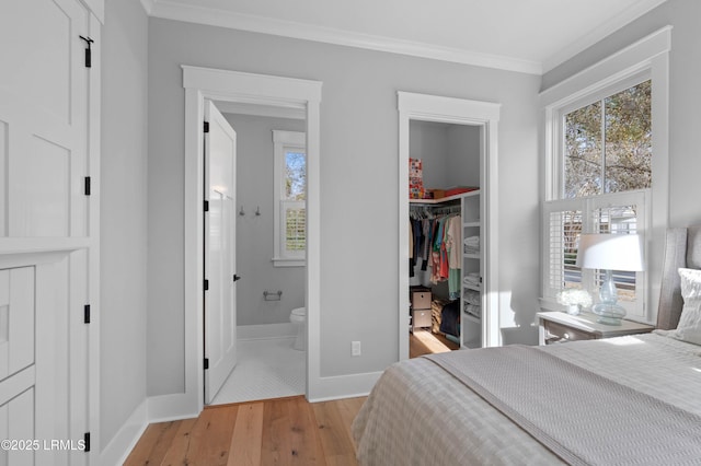 bedroom with light hardwood / wood-style flooring, a spacious closet, crown molding, ensuite bath, and a closet