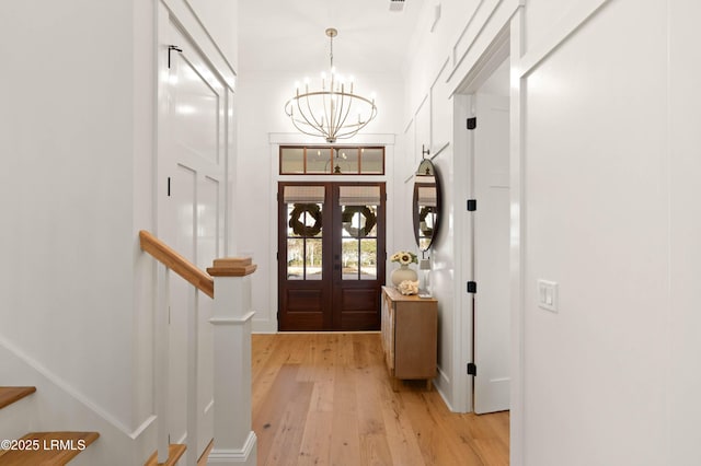 foyer featuring a chandelier, light wood-type flooring, and french doors