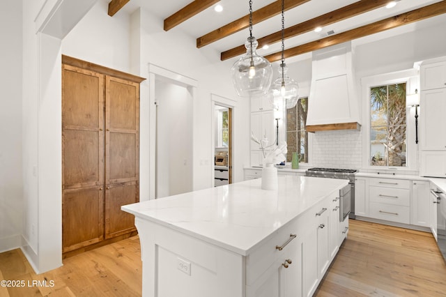 kitchen featuring high end stainless steel range oven, premium range hood, a kitchen island, and white cabinets