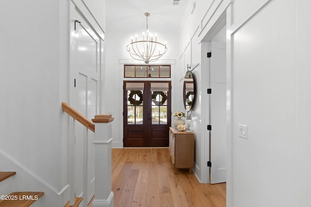 foyer featuring french doors, an inviting chandelier, and light wood-type flooring