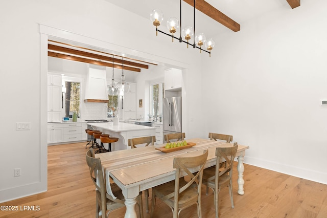 dining area with beam ceiling and light hardwood / wood-style flooring