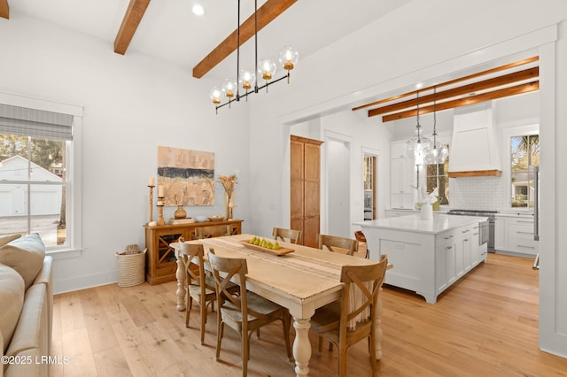 dining space with beam ceiling, an inviting chandelier, and light hardwood / wood-style floors