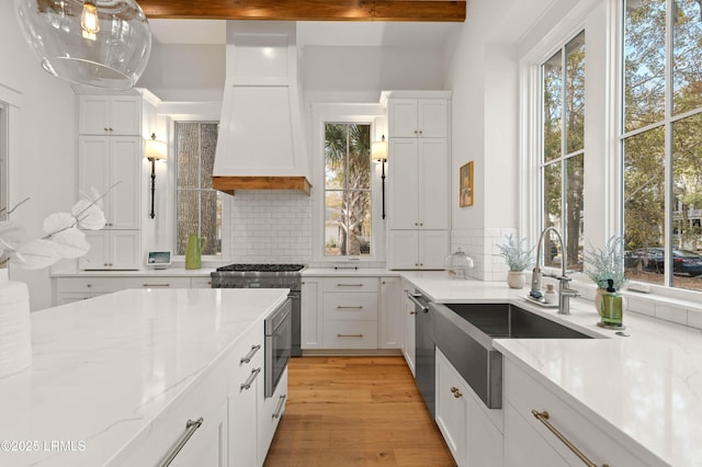 kitchen featuring white cabinetry, light stone countertops, custom range hood, and decorative backsplash