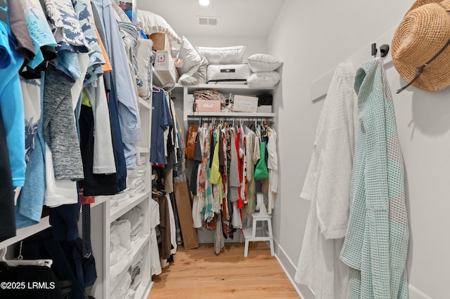 walk in closet with light hardwood / wood-style floors