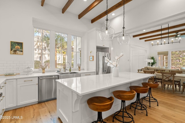 kitchen featuring pendant lighting, sink, white cabinetry, stainless steel appliances, and a kitchen island