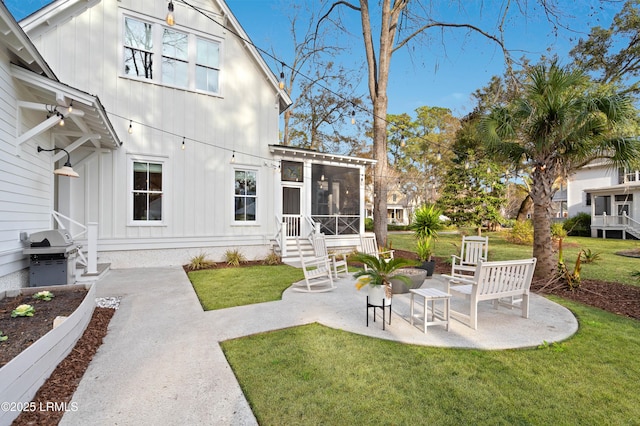 rear view of house featuring a lawn, a sunroom, and a patio