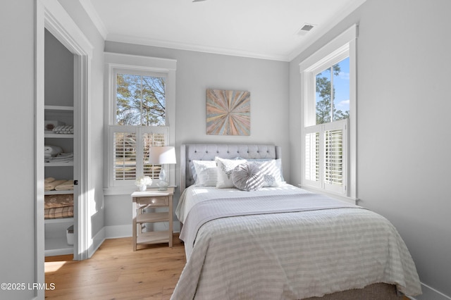 bedroom featuring ornamental molding and light hardwood / wood-style flooring