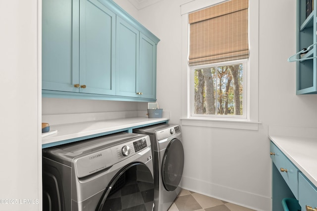 clothes washing area with cabinets and washing machine and clothes dryer