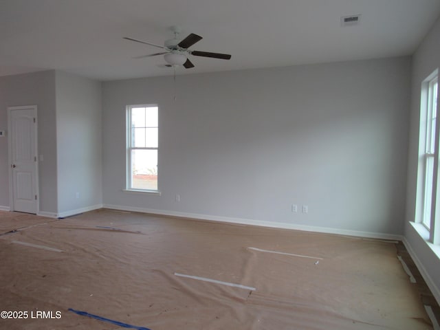 empty room featuring a ceiling fan, visible vents, and baseboards