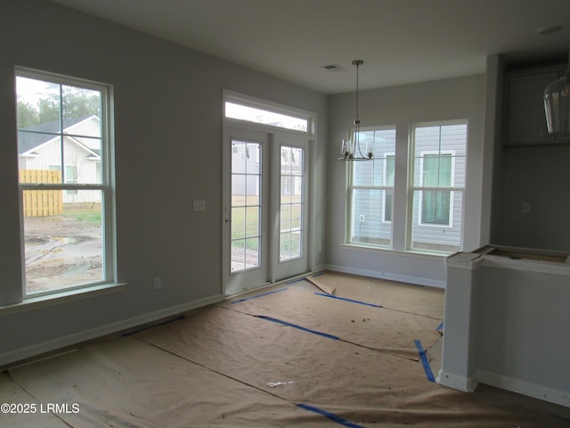 unfurnished dining area with a chandelier, visible vents, and baseboards