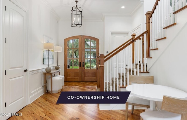 foyer featuring a chandelier, stairs, ornamental molding, french doors, and wood finished floors