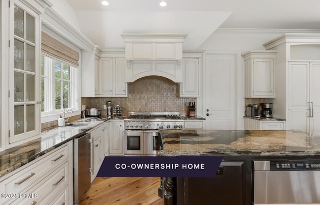 kitchen with decorative backsplash, stainless steel appliances, dark stone counters, and a sink