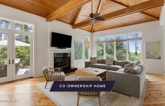 living room with french doors, a fireplace with raised hearth, and light wood finished floors