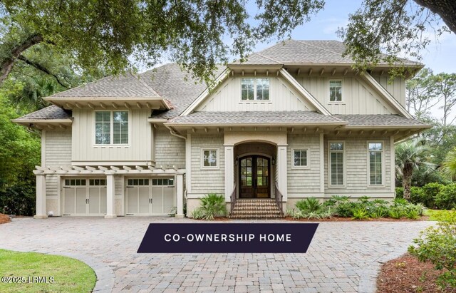 view of front facade with french doors, decorative driveway, a garage, and a shingled roof