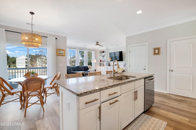 kitchen with sink, stainless steel dishwasher, pendant lighting, a kitchen island with sink, and white cabinets