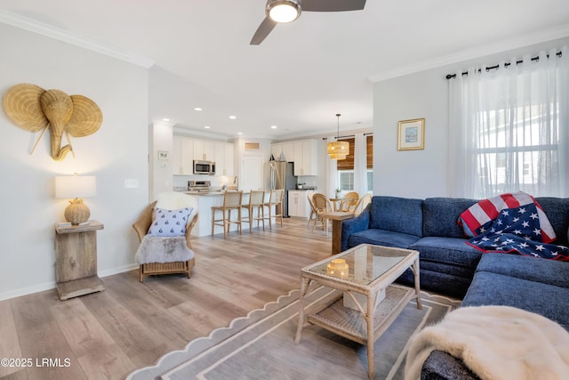 living room with crown molding, ceiling fan, and light hardwood / wood-style flooring