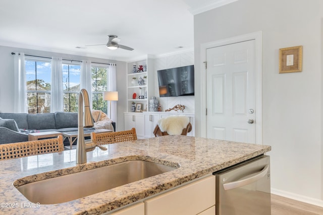 kitchen featuring dishwasher, sink, ceiling fan, light stone counters, and crown molding