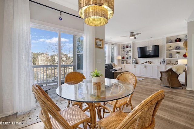 dining room with ornamental molding, ceiling fan with notable chandelier, light hardwood / wood-style floors, and built in shelves