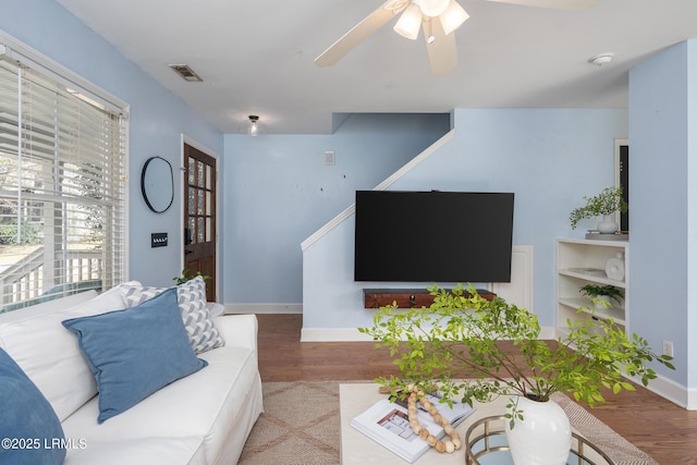 living area with ceiling fan, wood finished floors, visible vents, and baseboards