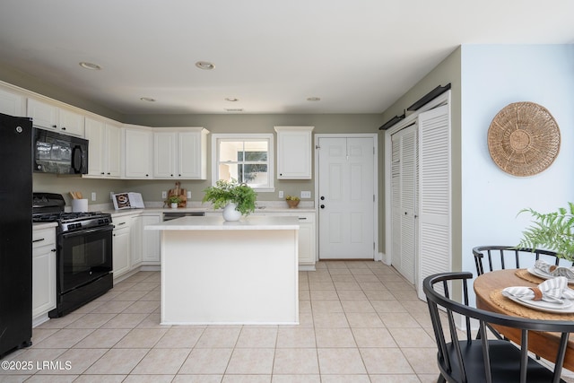 kitchen with a center island, light tile patterned floors, light countertops, white cabinetry, and black appliances