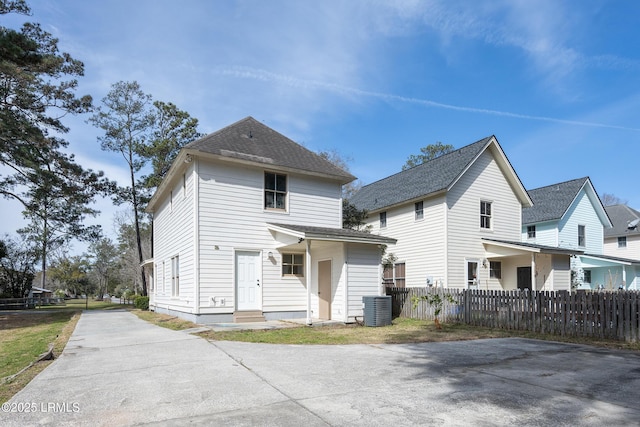 back of house featuring a shingled roof, fence, and central air condition unit