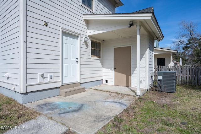 property entrance with a patio area, fence, and central AC unit