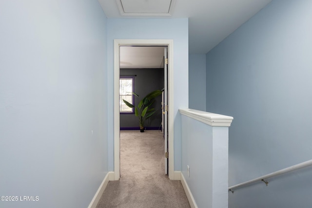 hallway with carpet floors, an upstairs landing, and baseboards