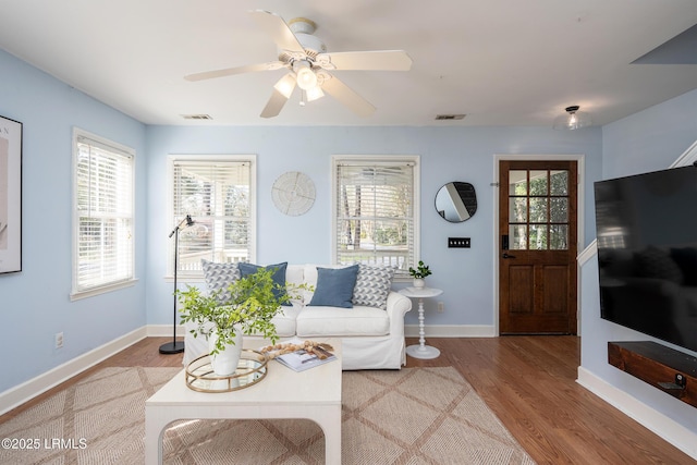 living area featuring a healthy amount of sunlight, visible vents, and wood finished floors