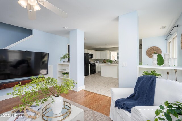 living area featuring light wood-style floors, visible vents, and a ceiling fan