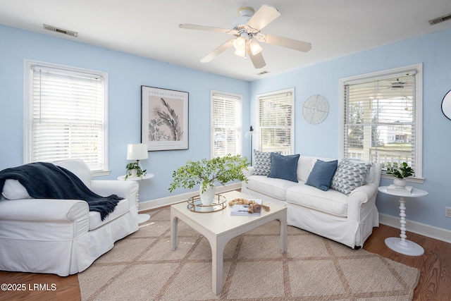 living room with ceiling fan, wood finished floors, visible vents, and baseboards