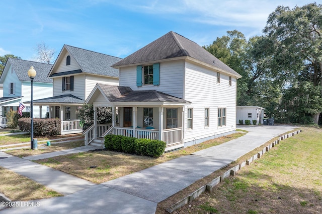 view of front of house with a shingled roof, a front yard, and covered porch