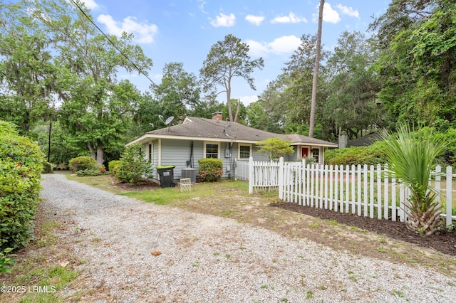 117 Elliott St, Beaufort, SC 29902 - view of front facade with fence, gravel driveway, view of scattered trees, and a chimney