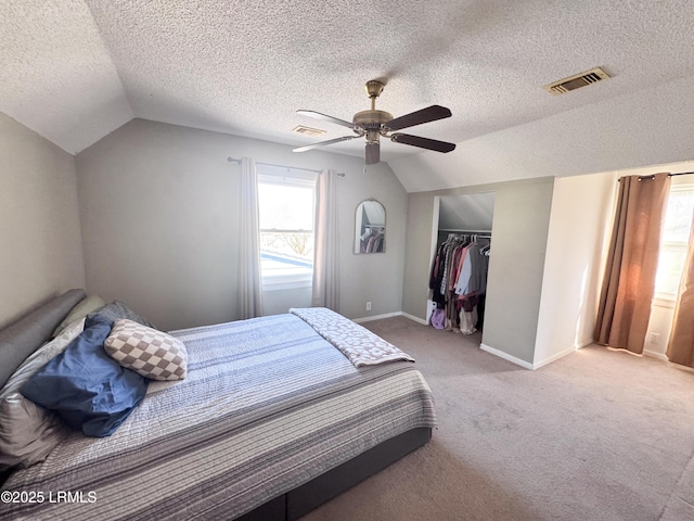 carpeted bedroom with a closet, visible vents, a ceiling fan, vaulted ceiling, and baseboards