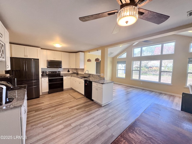 kitchen featuring stone counters, open floor plan, a sink, and black appliances