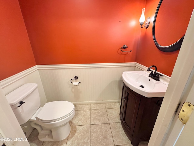 bathroom featuring toilet, tile patterned floors, vanity, and wainscoting