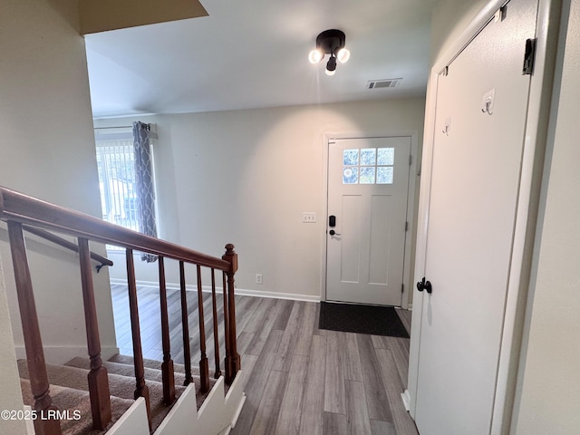 foyer entrance with stairs, visible vents, baseboards, and wood finished floors