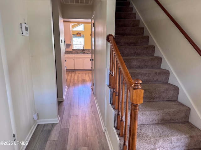 stairway with baseboards, visible vents, and wood finished floors