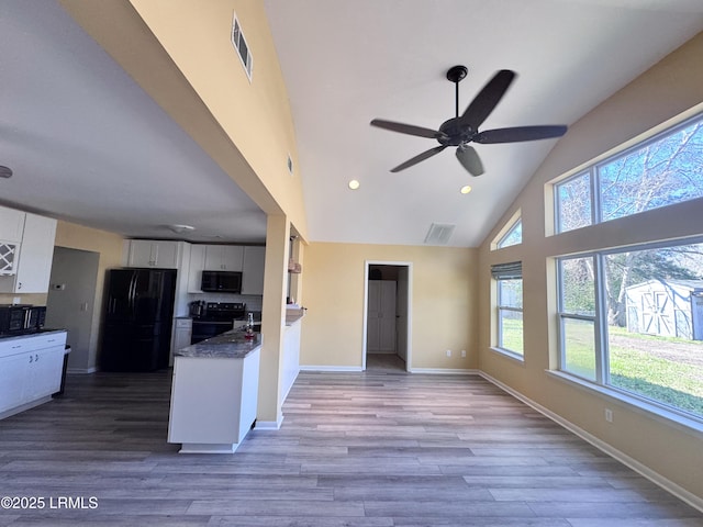 kitchen with black appliances, visible vents, white cabinetry, and open floor plan