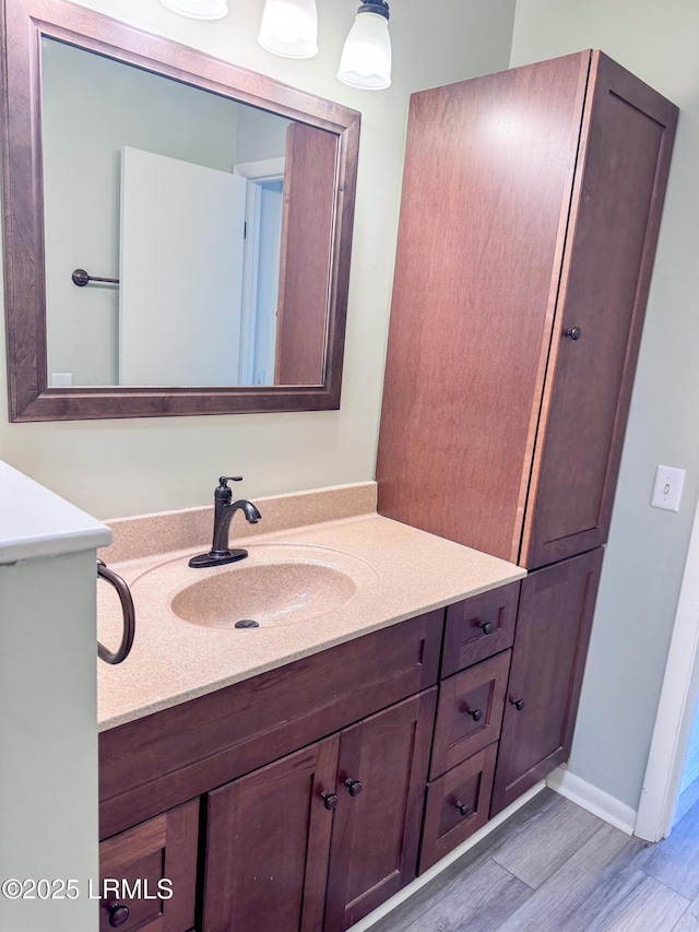 bathroom with wood finished floors, vanity, and baseboards