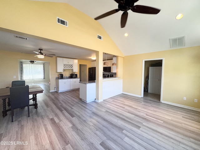 kitchen with open floor plan, light wood finished floors, visible vents, and white cabinetry