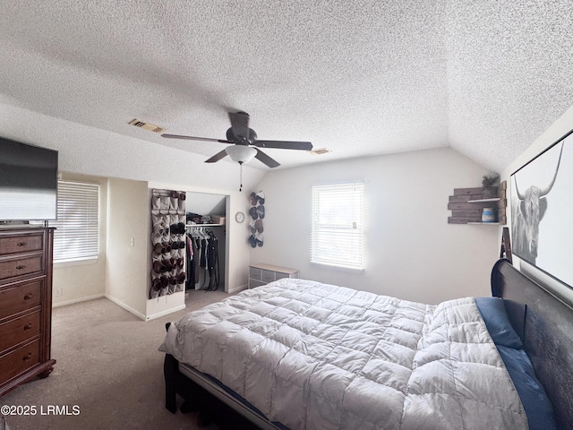 carpeted bedroom with a ceiling fan, lofted ceiling, a closet, and visible vents