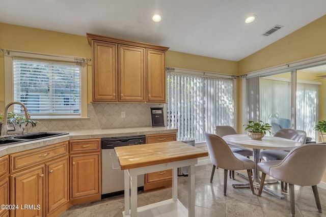 kitchen featuring vaulted ceiling, sink, stainless steel dishwasher, and decorative backsplash