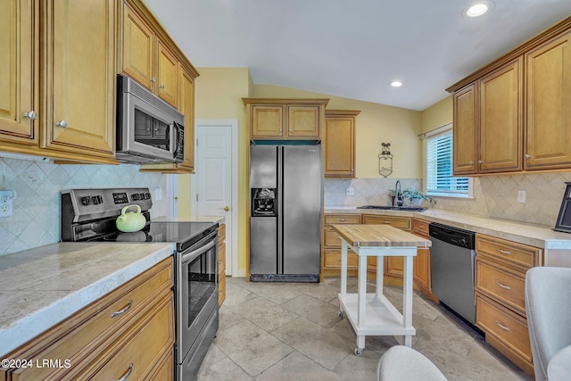 kitchen featuring stainless steel appliances, lofted ceiling, sink, and decorative backsplash